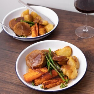 Vegan Garlic & Rosemary Roast by Sgaia Foods served sliced with roast vegetables and gravy.