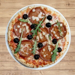 Veggyness vegan salami served on pizza with vegan cheese, rocket and olives.