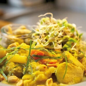 Vegan Unsweetened Cooking Cream by Schlagfix served in a yellow curry with carrots, potatoes, sprouts and more.