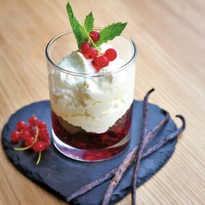 Vegan Sweetened Whipping Cream by Schlagfix served in a glass on top of a berry compote.