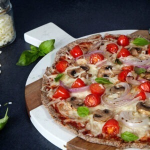 Vegan Grated Mozzarella Cheese Alternative by Violife melted onto pizza with mushrooms, tomatoes, red onion and fresh basil.