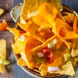 Vegan Cheddar Cheese Alternative Block by Greenvie served melted into a sauce for nachos with fresh tomato and onion.