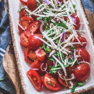 Vegan Grated Mozzarella Cheese Alternative by Greenvie served on top of fresh tomatoes, red onion and salad.