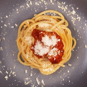 Vegan Gondino Grated Parmesan Cheese Alternative by Pangea Foods served on vegan spaghetti Bolognese.