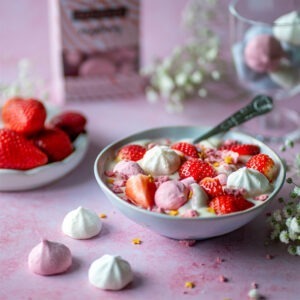 Vegan Raspberry Meringues by London Apron served in a bowl of vegan ice cream with strawberries.