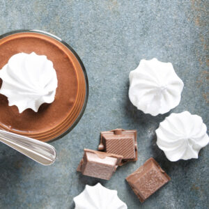 Vegan Vanilla Meringues by London Apron served on top of a vegan hot chocolate with chocolate blocks.