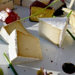 Vegan Camembert cheese alternative by Mouse's Favourite shown sliced on a vegan cheeseboard with grapes.