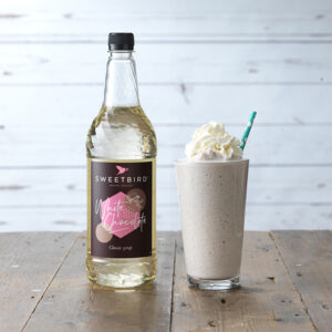 Vegan White Chocolate Classic Syrup by Sweetbird served in a vegan milkshake topped with a vegan cream alternative.
