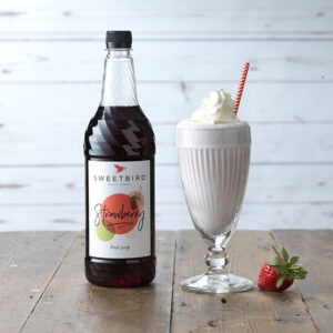 Vegan Strawberry Fruit Syrup by Sweetbird served in a vegan milkshake topped with a vegan cream alternative.