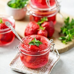 Vegan Strawberry Jelly by Just Wholefoods served in jars topped with fresh strawberries and mint.
