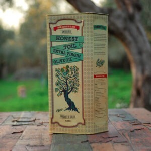 Vegan Unfiltered Extra Virgin Olive Oil by Honest Toil. Shown on a table in an olive grove.