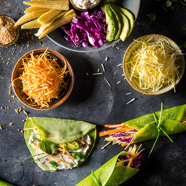 Grated Cheddar Cheese Alternative by GreenVie served with vegetables in mini spinach pancake wraps.