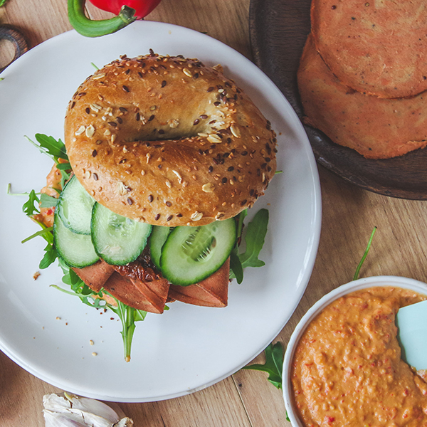 Vegan Dried Ham by Plenty Reasons served with rocket and cucumber on a seeded bagel.