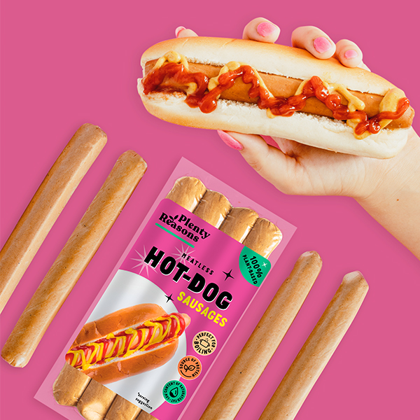 Vegan Hot Dog Sausages by Plenty Reasons shown in a bun with tomato ketchup and mustard.
