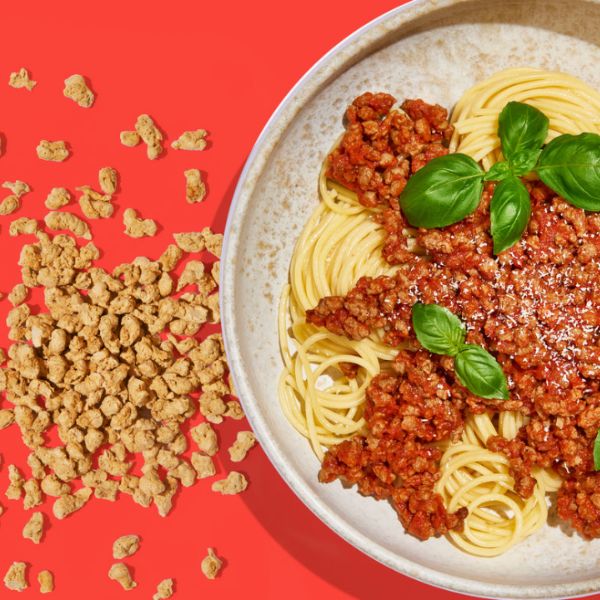 Vegan Bolognese Instant Mince by Sunflower Family served on top of spaghetti with fresh basil.