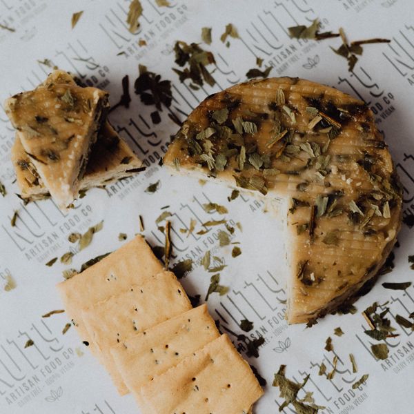 Vegan Aged with Wild Garlic by Nutty Artisan Co shown next to some crackers and scattered with dried wild garlic.