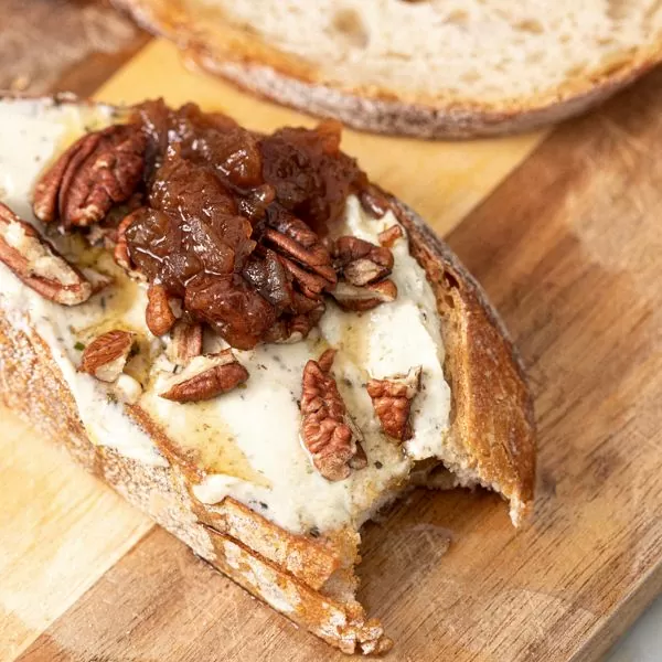 Vegan Garlic and Herb Spread by Honestly Tasty served on crusty bread with pecans and onion chutney.