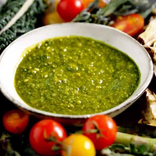 Vegan Raw Basil Pesto by Seggiano shown in a bowl, surround by tomatoes.