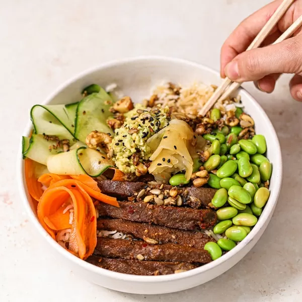 Vegan Original Flavour Steaks by Sgaia served in a Buddha bowl with ribbon carrots, cucumber, edamame beans, seeds, and pickled ginger.