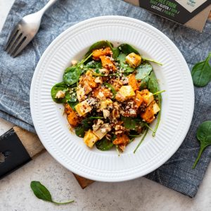 Vegan Camembert Block by GreenVie. Shown cubed on a pumpkin and spinach salad, topped with nuts and seeds.